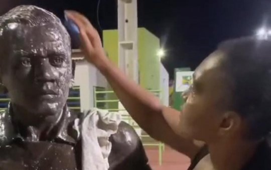 Prima de Daniel Alves faz limpeza da estátua pichada em Juazeiro