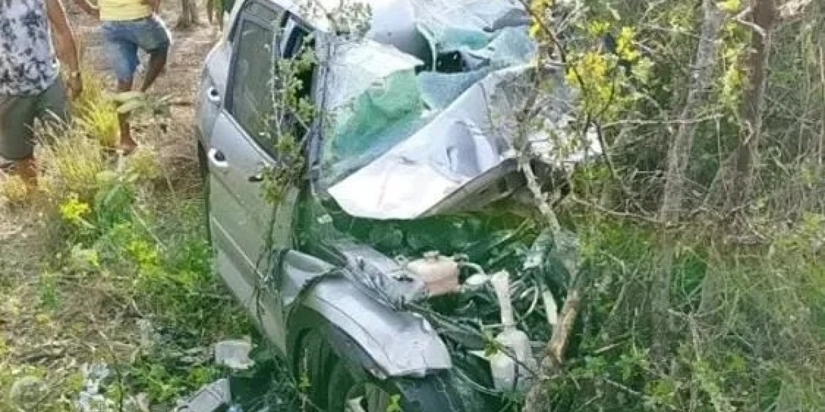 A imagem mostra um carro destruído após um acidente na BR-324