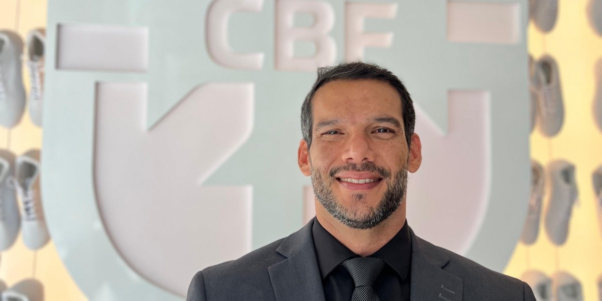 Samir Xaud em frente a escudo da CBF