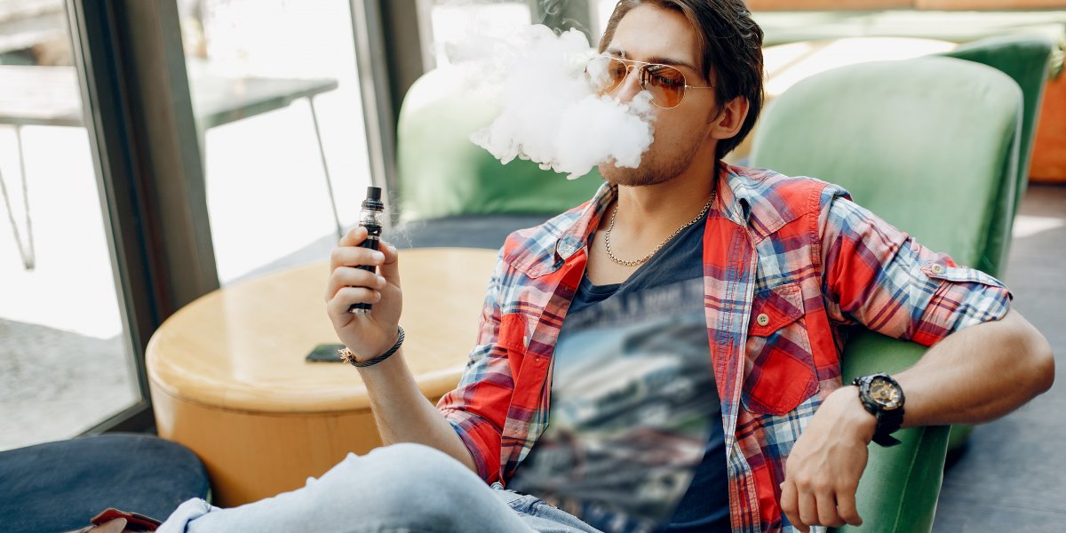 Imagem ilustrativa de um homem usando cigarro eletrônico