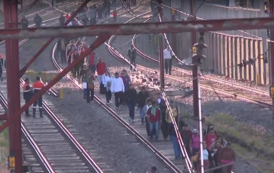 Passageiros caminham pelos trilhos após paralisação de linhas de trem em São Paulo